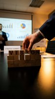 Business executive arranging wooden blocks spelling VISION during corporate strategy meeting with presentation charts in background.