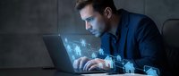 Professional businessman working on laptop with holographic digital interface displaying data analytics and virtual technology in modern office environment.