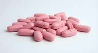 Pink oval tablets scattered on white background for pharmaceutical and healthcare design projects.