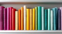 Colorful books arranged in rainbow spectrum order on white bookshelf, spines showing gradient from pink through yellow to turquoise and purple creating vibrant display.