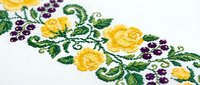 Traditional floral embroidery with yellow roses and purple grapes on white fabric. Decorative needlework pattern for textile crafts and home decor projects.