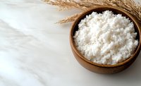 Wooden bowl filled with white flour and dried wheat stalks on marble surface, ready for baking and cooking projects.
