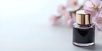 Luxury black perfume bottle with gold cap against white background, decorated with delicate pink cherry blossoms, creating elegant cosmetic composition.