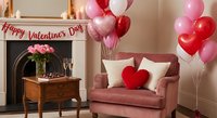 Romantic Valentine's Day living room setup with pink armchair, heart balloons, roses and festive decorations for holiday celebration and love themed interior design.