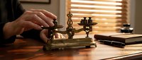 Professional businessman using vintage brass balance scale at wooden desk in warm office setting for legal or financial decision making.