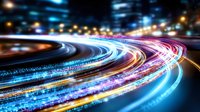 Long exposure of curved highway at night with colorful light trails creating dynamic motion effect, blue and pink streaks against dark background.