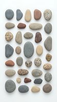 Collection of smooth river rocks and pebbles in various natural colors arranged on white background for spa, zen meditation, and wellness design projects.