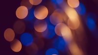 Abstract bokeh lights background with warm orange and cool blue circular highlights creating dreamy atmospheric effect for creative projects and designs.