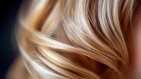Luxurious golden blonde hair strands in flowing motion against dark background, showcasing smooth, silky texture and professional hair care styling results.