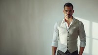 Confident young Caucasian male model in elegant white shirt and light gray waistcoat standing in dramatic natural window lighting perfect for fashion and business lifestyle advertising.