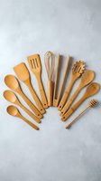 Wooden kitchen utensils set arranged on concrete background. Natural bamboo cooking tools including spoons, spatulas, whisk for culinary preparation.