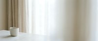 Minimalist workspace with white ceramic mug on clean desk, soft natural light from window with beige curtains, serene and calm atmosphere for productivity and focus.