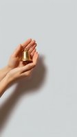 Hands gently holding golden bell against neutral background for mindfulness meditation spiritual wellness and holiday celebration concepts.