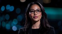 Asian businesswoman wearing glasses and black blazer smiling confidently against blurred city lights background, professional corporate portrait with bokeh effect.