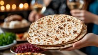 Freshly baked flatbread served at middle eastern dinner gathering with traditional sides, wine glasses and warm bokeh lights in background.