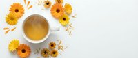 Cup of herbal tea surrounded by dried chamomile and sunflower blooms on white background, ideal for wellness and beverage marketing.