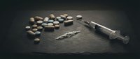 Drug addiction concept with pills powder and syringe on dark surface for awareness campaigns and educational materials about substance abuse prevention.