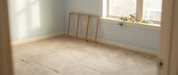 Empty room with light wooden flooring, white walls, and natural sunlight from window. Wooden ladder leaning against wall. Suitable for renovation, real estate, and interior design projects.