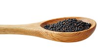 Black peppercorns in wooden bamboo spoon isolated on white background, macro shot of aromatic spice for cooking and seasoning food preparation.