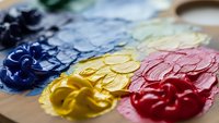Artist oil paints mixed on palette with brush strokes in vibrant colors including blue yellow red for creative artwork and painting projects.