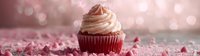 Red velvet cupcake with cream cheese frosting and heart sprinkles on pink glitter background with bokeh lights, romantic dessert banner format.