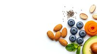 Healthy superfood ingredients with nuts, berries, avocado and seeds arranged on white background for nutritious meal preparation and clean eating.