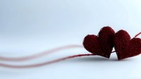 Two red woolen heart shapes lying together on white surface with soft shadow and gentle curved line, romantic minimal composition for Valentine's day cards.