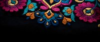 Vibrant Mexican embroidered floral pattern with colorful thread work on black fabric background for traditional textile and craft projects.