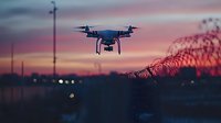 Modern drone flying at sunset with dramatic purple and pink sky over urban landscape with bridge and city lights creating atmospheric aerial photography scene.