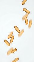 Golden vitamin capsules falling through air with soft shadows on white background for health and wellness supplement advertising.