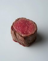 Juicy rare beef tenderloin steak cut showing pink center and browned exterior on neutral background, isolated food photography for restaurant menus and cooking blogs.