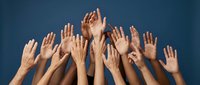 Diverse group of hands raised up against blue background showing unity, teamwork and volunteer spirit for community engagement and social causes.