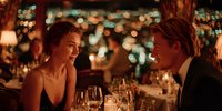 Elegant couple enjoying romantic dinner date at upscale restaurant with wine glasses and warm ambient lighting creating intimate atmosphere for special occasion.
