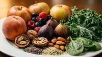 Fresh organic produce featuring colorful apples, mixed berries, leafy kale, spinach, walnuts, almonds, and chia seeds arranged on white plate for healthy eating.