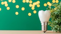 Dental implant with green plant on emerald background with golden bokeh lights. Modern dentistry and oral health concept for medical presentations.