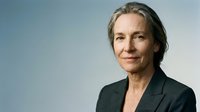 Professional mature Caucasian businesswoman in dark suit with confident expression against neutral background for corporate presentations.