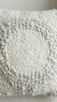 Cream textured throw pillow with chunky knit weave and spiral pattern detail, suitable for home decor, interior design projects, and lifestyle photography.