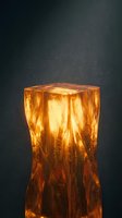 Glowing amber crystal formation with internal light effects and magical particles floating in dark atmospheric background for fantasy designs.
