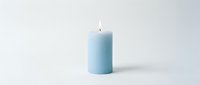 Soft blue pillar candle with a glowing flame on a clean white background, evoking calm and serenity for home decor and wellness concepts.
