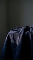 Crumpled indigo linen fabric draped over edge against dark background, showcasing textile texture and natural folds for design and fashion projects.