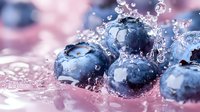 Fresh blueberries splashing in water with droplets and bubbles against pink background, macro photography showing detailed texture of berries and water motion.
