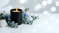 Black candle burning with white flowers and eucalyptus leaves on marble surface with soft bokeh lights creating elegant spa atmosphere for relaxation.