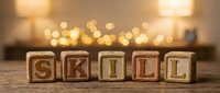 Wooden blocks spelling skill with warm bokeh lights in background, suitable for education, training, professional development and business concepts.