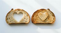 Two slices of artisan bread with heart-shaped cutouts on white background, perfect for romantic breakfast, love concept, bakery products, food styling.