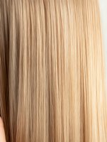 Close-up of straight blonde hair texture showing smooth, silky strands with natural gradient from darker to lighter tones, suitable for beauty and hair care marketing.