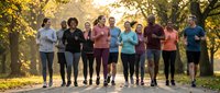 Diverse group of people jogging together in autumn park during golden hour sunrise, healthy lifestyle and fitness community concept for wellness campaigns.