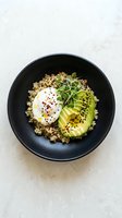 Healthy grain bowl with quinoa, sliced avocado, poached egg, microgreens and red pepper flakes in black bowl. Perfect for food blogs, nutrition websites and healthy eating content.