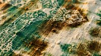 Close-up macro view of weathered canvas texture with green and brown paint layers showing artistic wear, cracking and aging effects for creative projects.