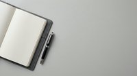 Open notebook with blank pages and pen on gray surface, suitable for business planning, journaling, and creative writing projects.