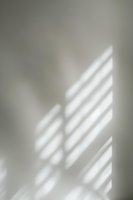 Soft window light and shadows cast on neutral gray wall creating minimalist abstract pattern, natural sunlight through blinds for modern interior design background.